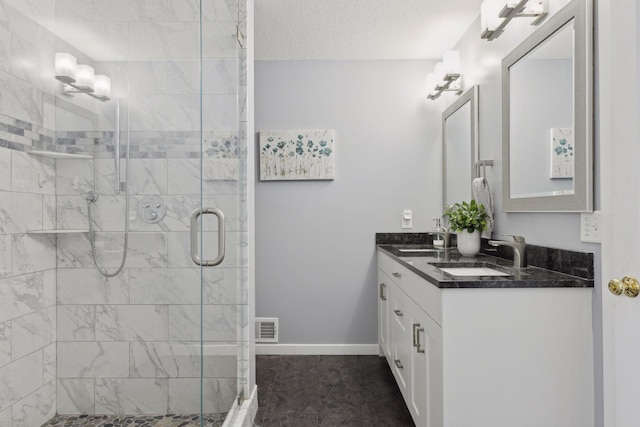 bathroom featuring vanity, a textured ceiling, and a shower with shower door