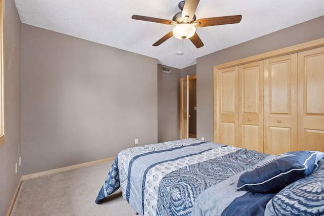 carpeted bedroom with a textured ceiling, ceiling fan, and a closet