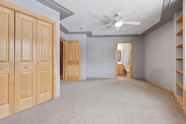 unfurnished bedroom with light carpet, crown molding, ensuite bath, and a closet