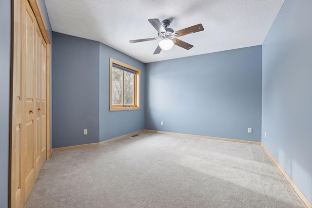 unfurnished bedroom with ceiling fan, carpet flooring, a textured ceiling, and a closet