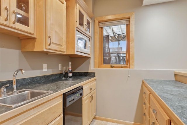 kitchen with light brown cabinetry, dishwasher, and sink