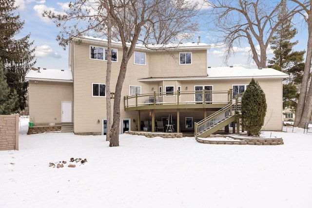 snow covered back of property featuring a wooden deck