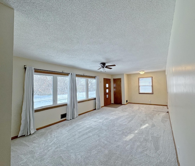 unfurnished living room with ceiling fan, plenty of natural light, and light carpet