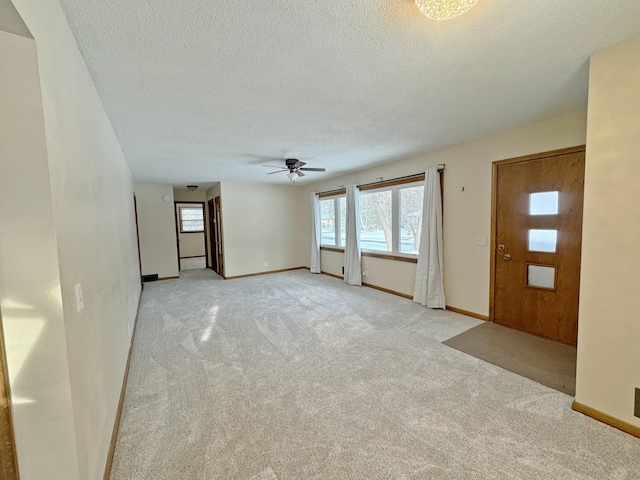 unfurnished living room featuring light carpet, a textured ceiling, and ceiling fan