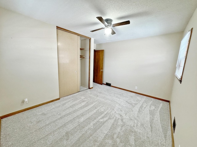 unfurnished bedroom featuring carpet, a textured ceiling, a closet, and ceiling fan