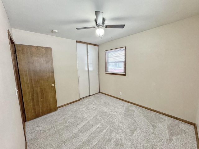 unfurnished bedroom featuring light carpet, a closet, and ceiling fan