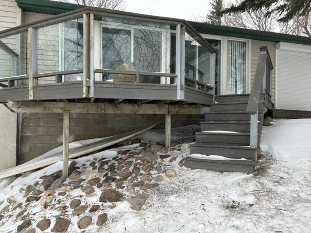 view of snow covered exterior featuring a wooden deck and a sunroom