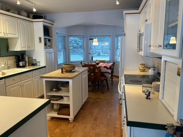 kitchen with decorative backsplash, white cabinetry, sink, and hanging light fixtures