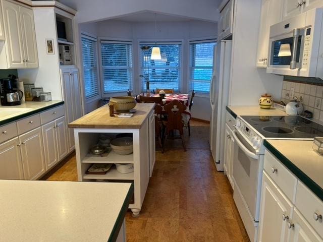 kitchen featuring decorative backsplash, wooden counters, white appliances, white cabinets, and a center island