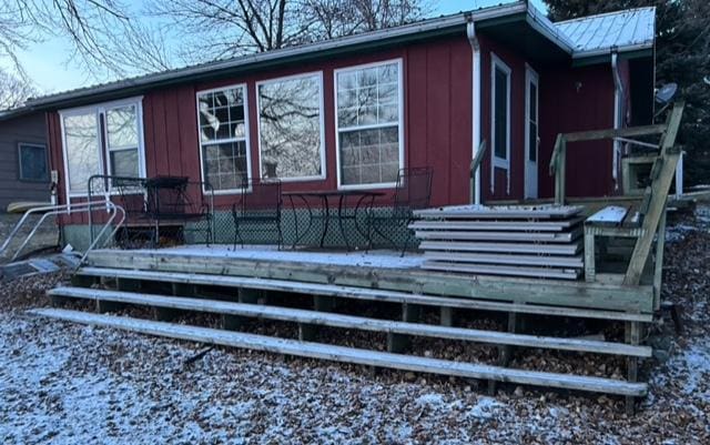 snow covered back of property featuring a wooden deck