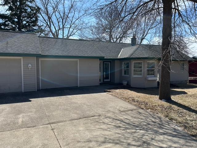 single story home with a chimney, an attached garage, a shingled roof, and aphalt driveway