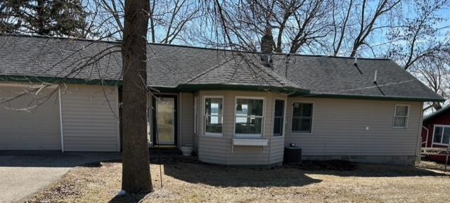 back of property featuring cooling unit, roof with shingles, a chimney, and an attached garage