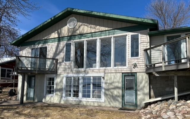 rear view of house with stucco siding and a balcony
