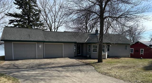 ranch-style home with a chimney, a garage, and concrete driveway