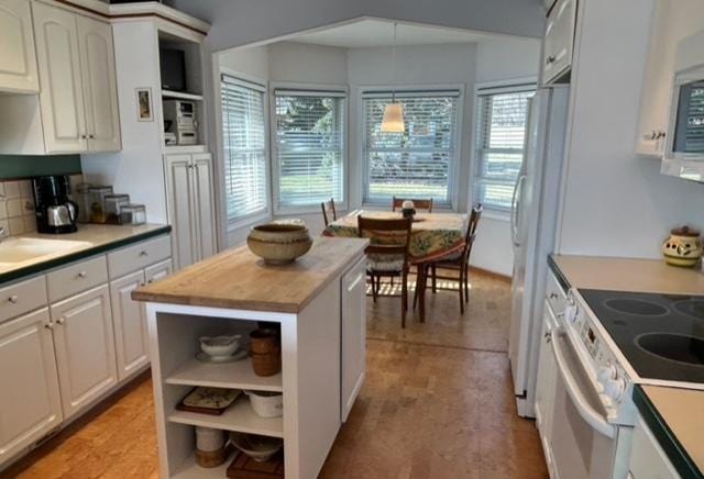 kitchen with white appliances, white cabinetry, open shelves, butcher block counters, and a sink