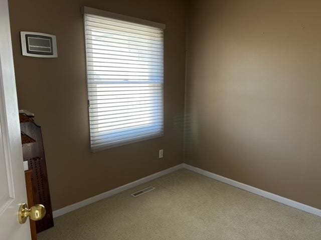 unfurnished room with visible vents, light colored carpet, and baseboards
