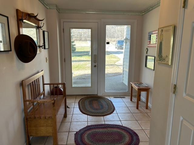 entryway with light tile patterned flooring and ornamental molding