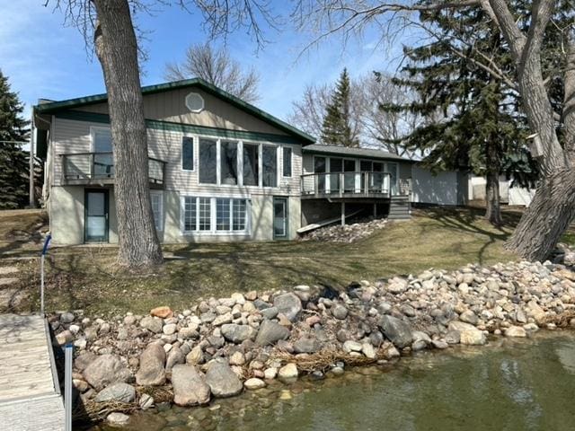 rear view of house featuring a deck with water view and a sunroom