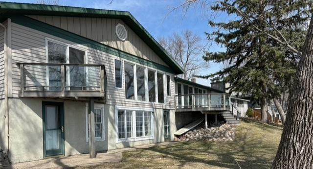 rear view of property with a deck and stucco siding