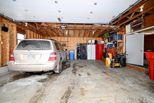 garage featuring white fridge with ice dispenser and a garage door opener