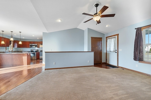 unfurnished living room featuring ceiling fan, sink, vaulted ceiling, and light carpet