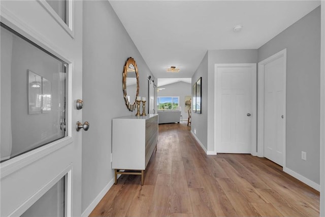 corridor featuring vaulted ceiling and light hardwood / wood-style flooring