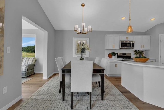 dining room with hardwood / wood-style flooring, lofted ceiling, and a chandelier