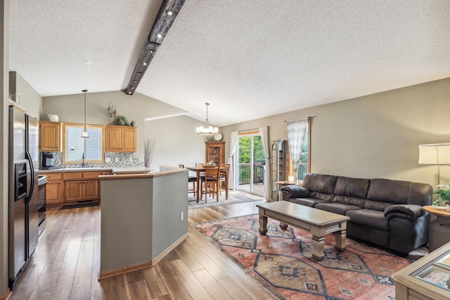 living room featuring vaulted ceiling with beams, hardwood / wood-style floors, a textured ceiling, and a notable chandelier