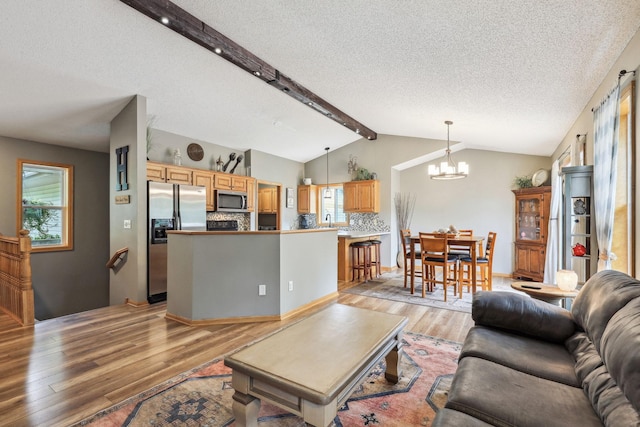 living room featuring a wealth of natural light, light hardwood / wood-style flooring, a textured ceiling, and a notable chandelier