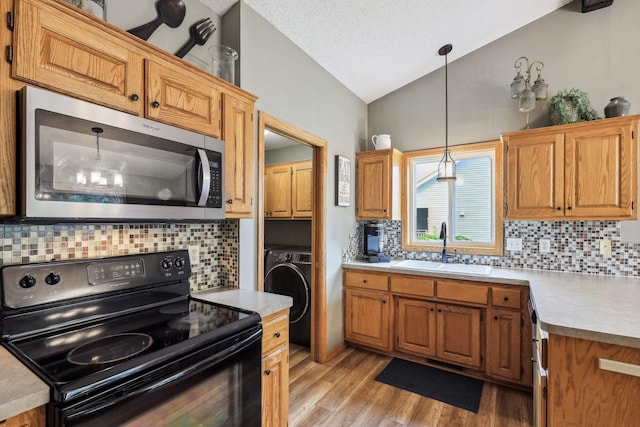 kitchen featuring black electric range oven, lofted ceiling, hanging light fixtures, sink, and washer / clothes dryer