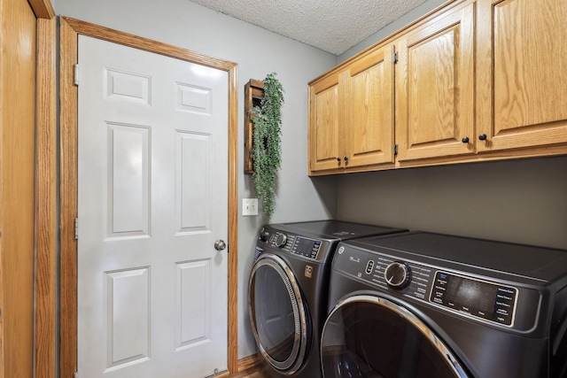 clothes washing area featuring cabinets, a textured ceiling, and washing machine and clothes dryer