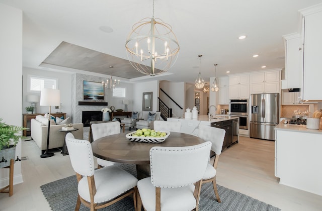 dining space featuring sink, light wood-type flooring, and an inviting chandelier