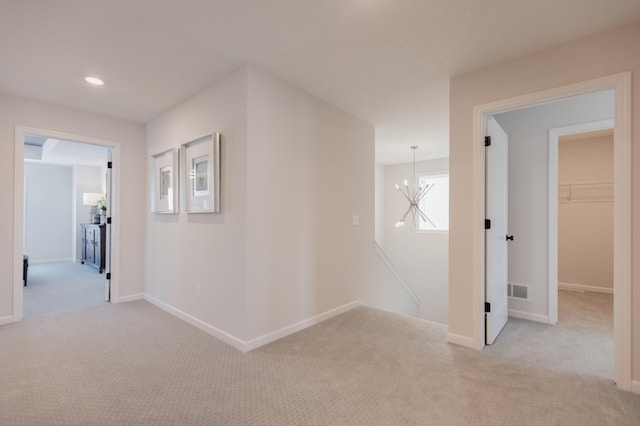 hallway featuring light carpet and an inviting chandelier