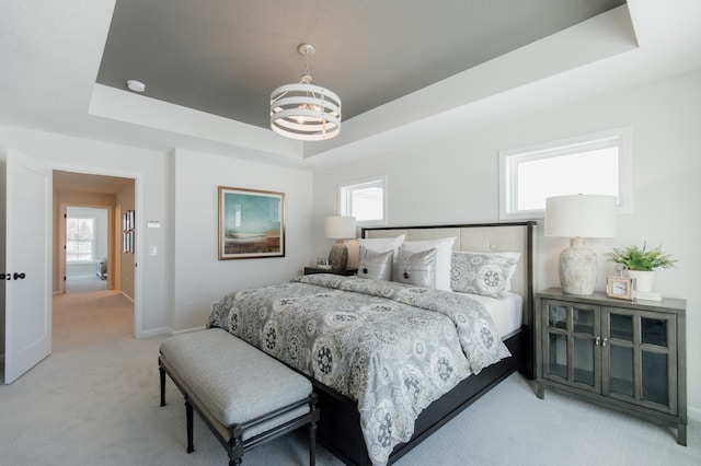 bedroom featuring a tray ceiling, light carpet, and a chandelier