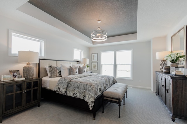 bedroom featuring a tray ceiling, a notable chandelier, and light colored carpet