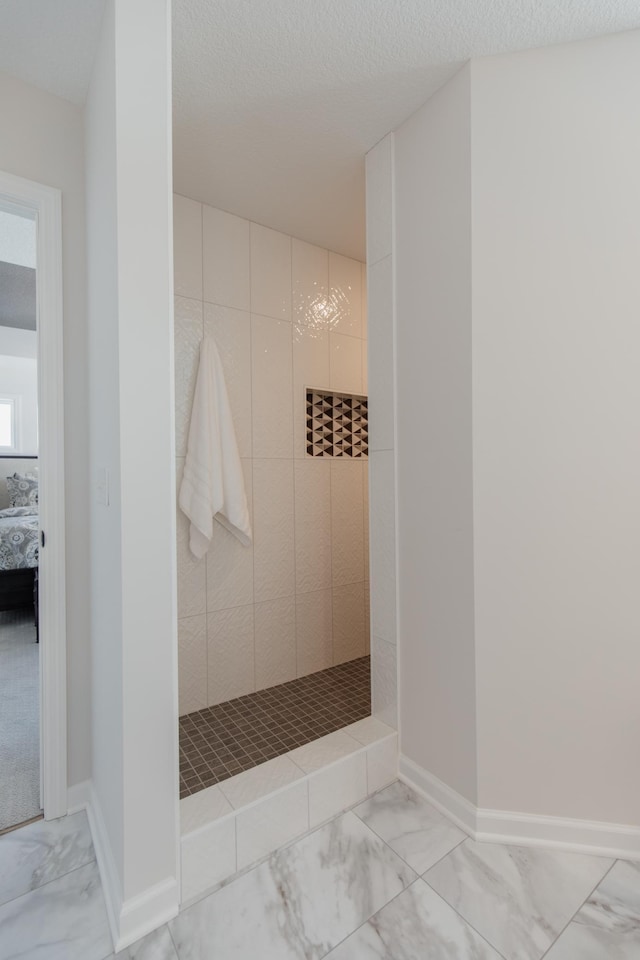 bathroom featuring a textured ceiling and tiled shower