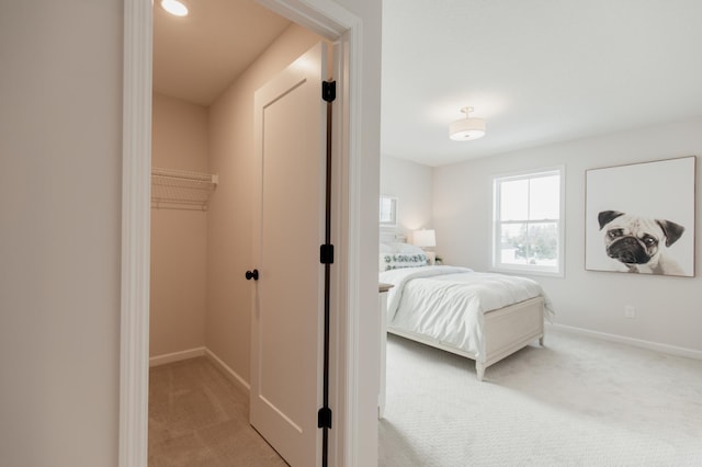 carpeted bedroom with a walk in closet and a closet