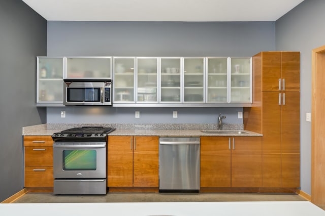 kitchen featuring light stone counters, sink, and appliances with stainless steel finishes