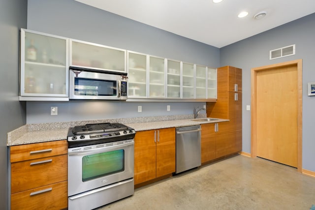 kitchen with sink, light stone countertops, and stainless steel appliances