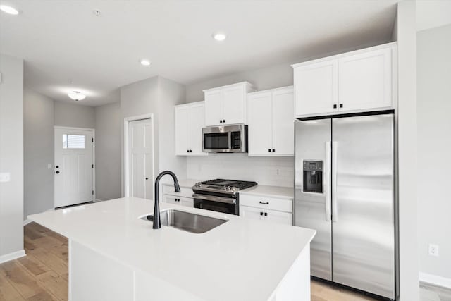 kitchen featuring stainless steel appliances, a center island with sink, white cabinetry, and sink