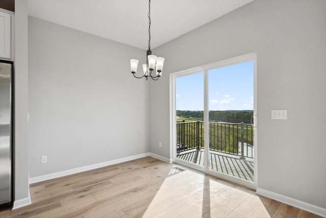 unfurnished dining area with a notable chandelier and light hardwood / wood-style flooring