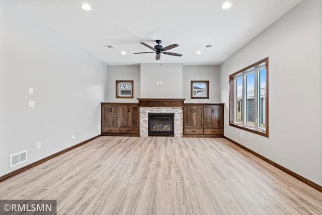 unfurnished living room featuring visible vents, baseboards, a fireplace, light wood-style floors, and a ceiling fan