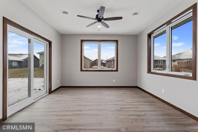 empty room featuring baseboards, a ceiling fan, and light wood finished floors