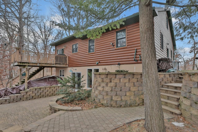 back of house with a wooden deck and a patio