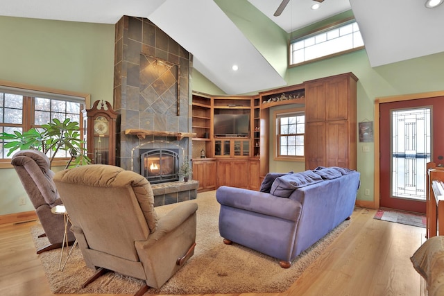 living room with a tile fireplace, a wealth of natural light, and light hardwood / wood-style floors