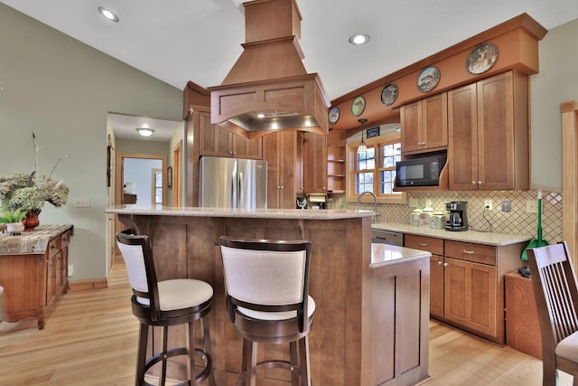 kitchen with appliances with stainless steel finishes, tasteful backsplash, lofted ceiling, a breakfast bar area, and a center island