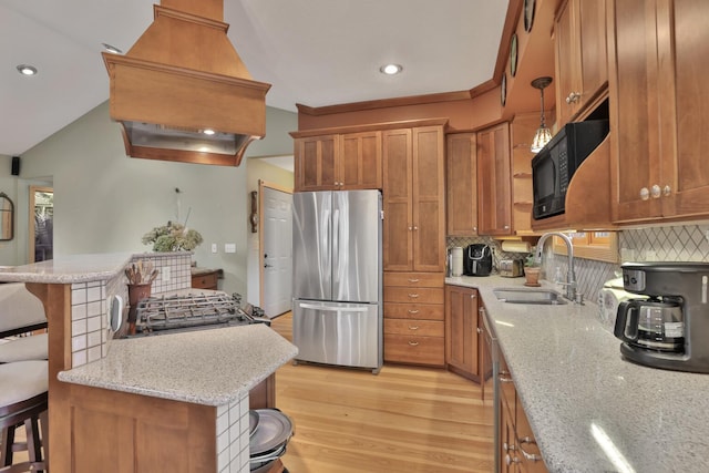 kitchen featuring sink, light stone counters, tasteful backsplash, appliances with stainless steel finishes, and a kitchen breakfast bar