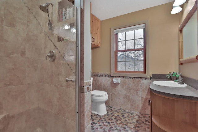 bathroom featuring tile patterned floors, toilet, a shower with shower door, tile walls, and vanity