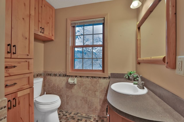 bathroom featuring vanity, tile walls, and toilet