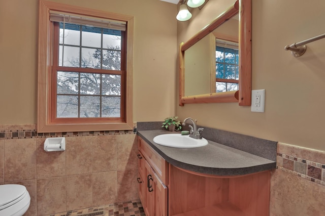 bathroom featuring vanity, tile walls, and toilet